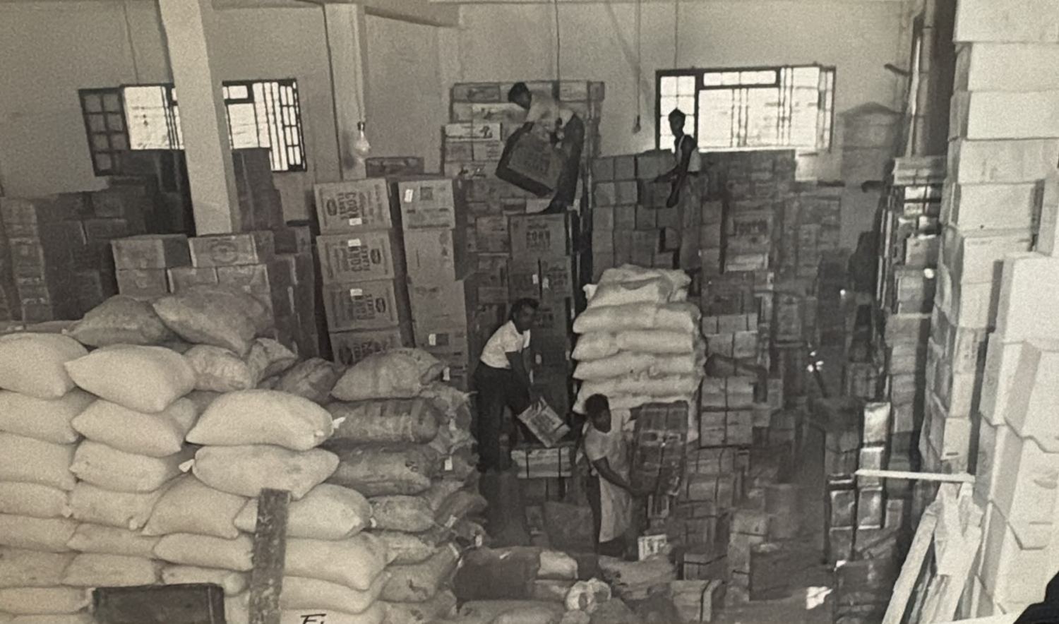 Trabajadores acomodando costales y cajas en la bodega de El Alba